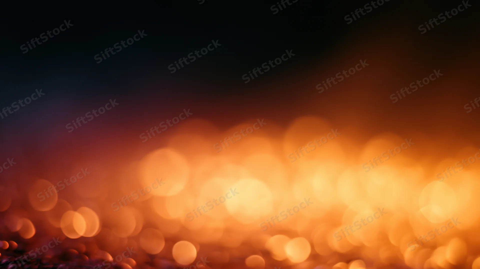 Blurred orange bokeh lights creating a warm glowing background with dark upper space for text or design