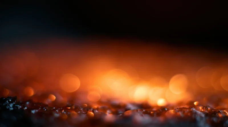 Glowing orange bokeh lights over dark textured surface at night