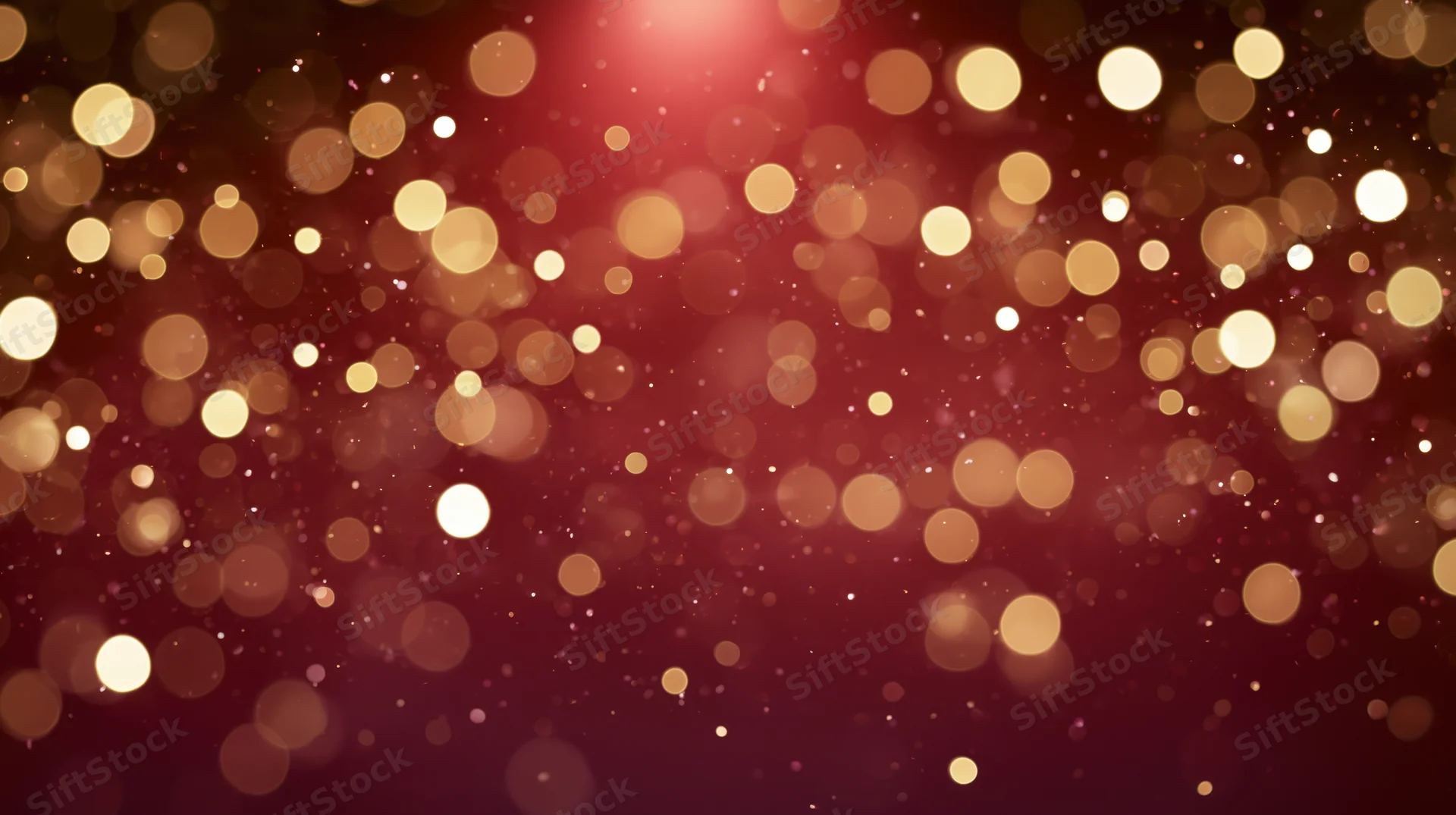 Golden bokeh lights glowing softly against a deep red background with scattered sparkles and warm glow