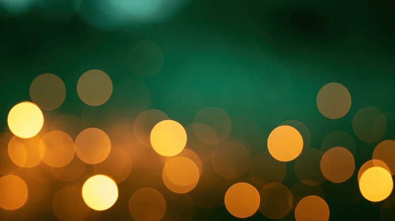 Blurred circular lights in warm orange and yellow tones against a dark green background, creating a soft glowing bokeh effect