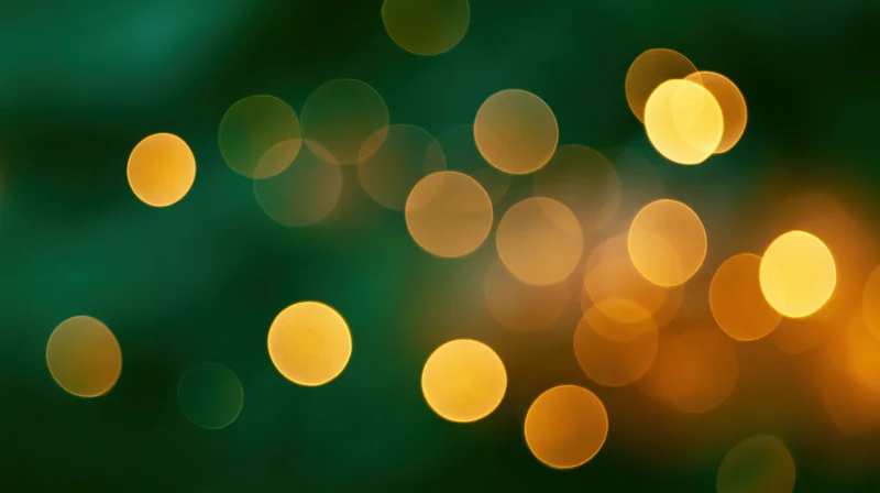 Golden bokeh lights scattered across a dark green background with soft glow and festive ambiance