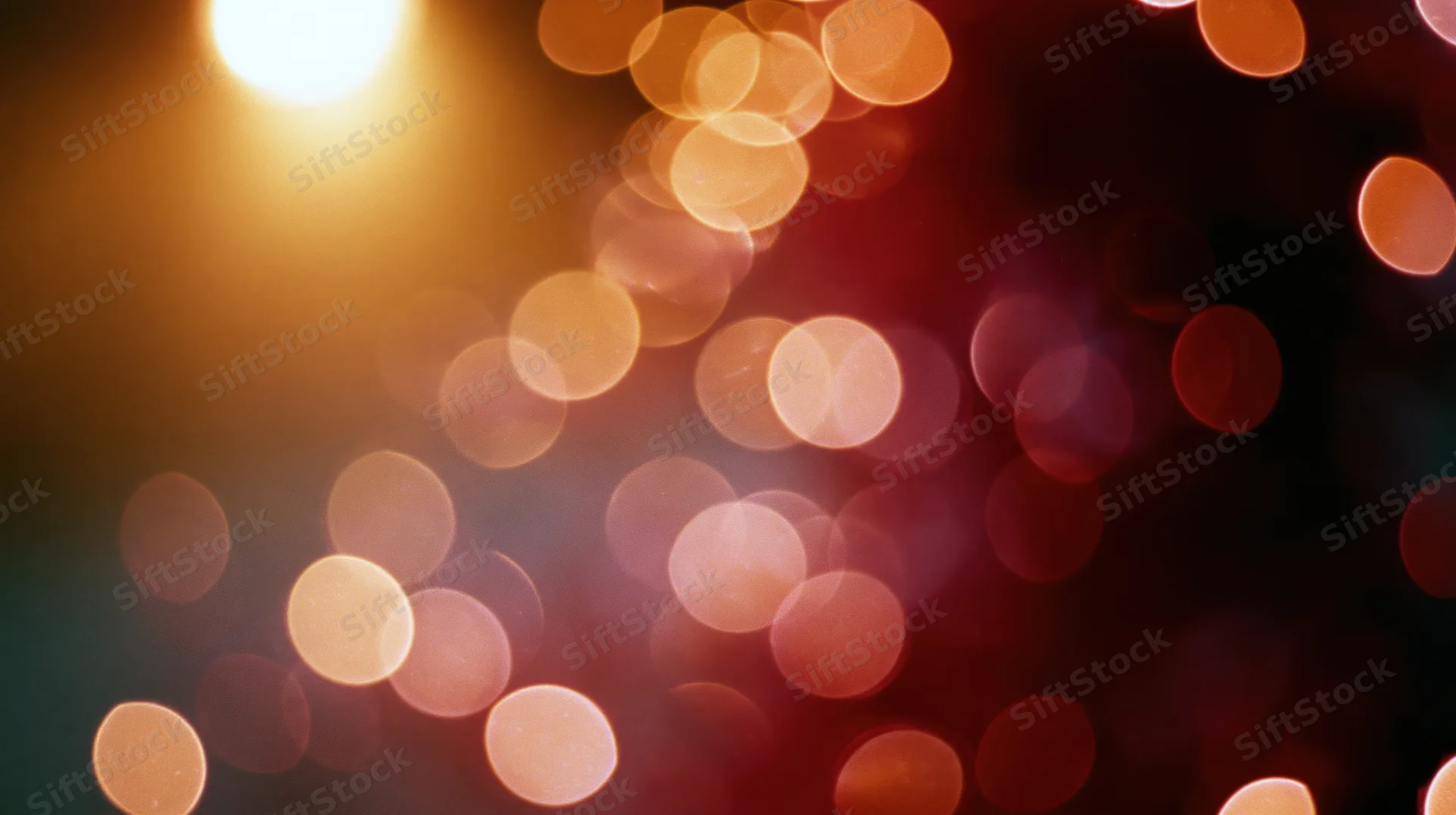 Blurred circular lights in warm golden and red tones against a dark background