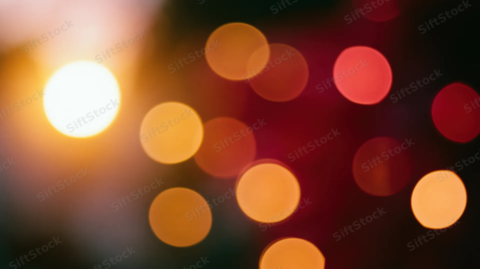 Blurred circular lights in warm orange and red tones against a dark background