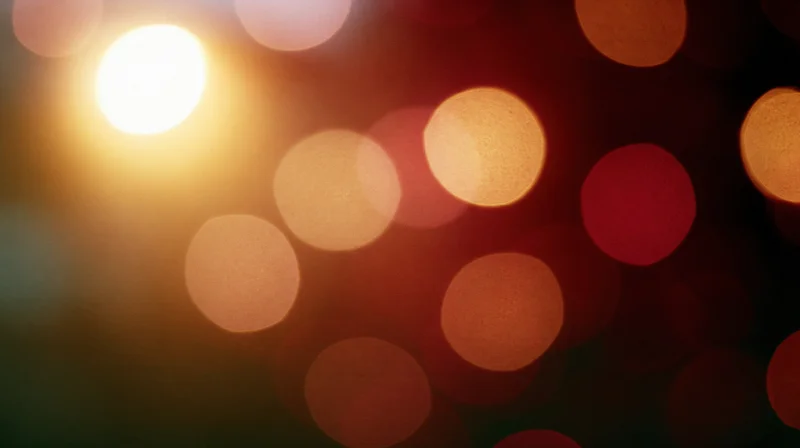 Blurred circular lights in warm tones arranged across a dark background with soft glow and bokeh effect