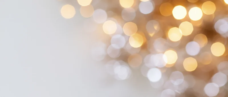 Blurred golden bokeh lights forming a soft glowing background with copyspace on the left
