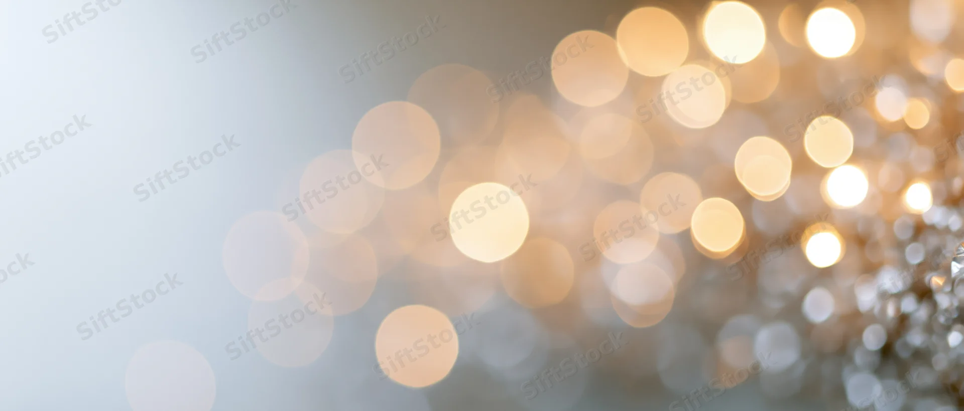 Blurred golden bokeh lights arranged diagonally across a soft background with copyspace on the left