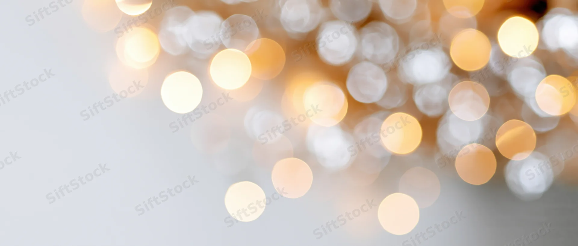 Blurred golden lights arranged in a diagonal pattern across a light background with copyspace on the left