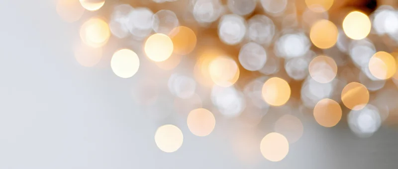 Blurred golden lights arranged in a diagonal pattern across a light background with copyspace on the left