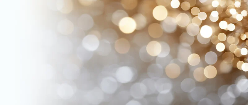 Blurred golden and white bokeh lights forming a festive background with copyspace on the left