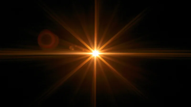 Bright golden starburst light flare centered on black background with radiating beams and lens flare effects