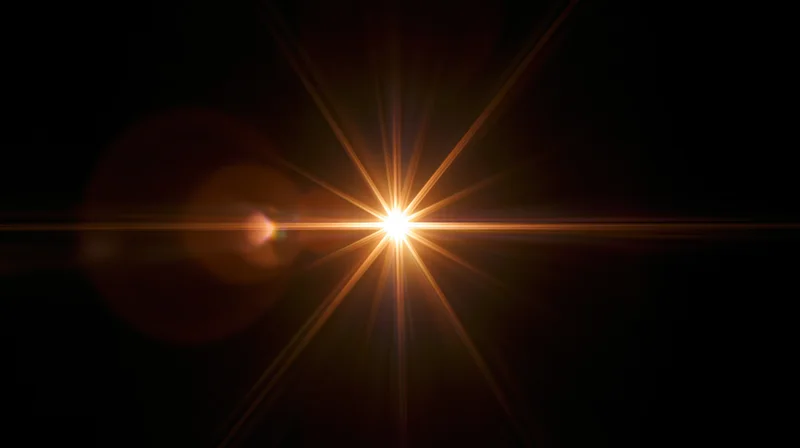 Bright starburst light effect radiating from center against dark background with lens flare and golden rays