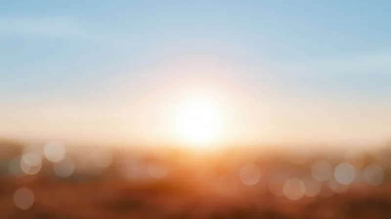 Blurred sunset over cityscape with bokeh lights and warm glow in the sky