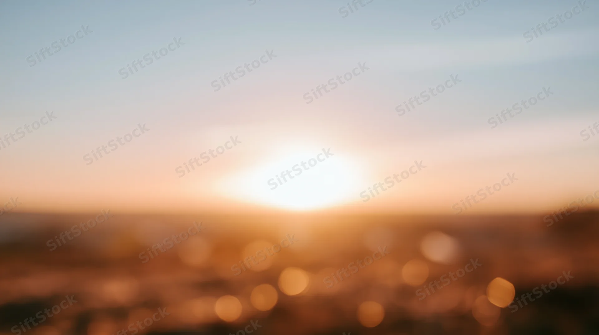 Blurred sunset over horizon with warm bokeh lights in sky