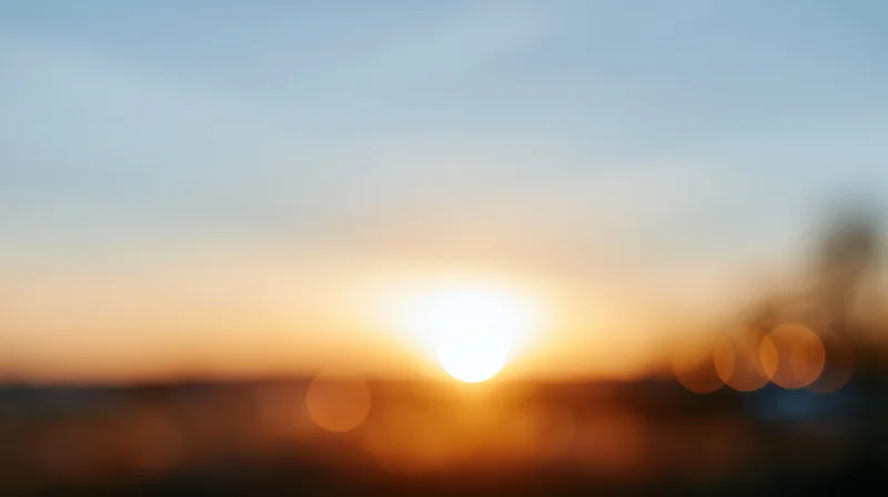 Blurred sunset over horizon with warm bokeh lights in sky