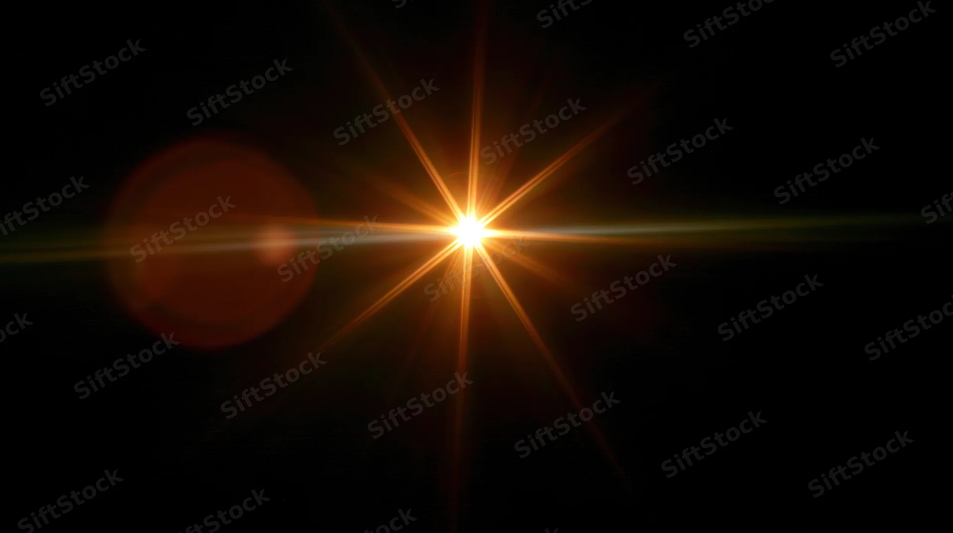 Bright orange starburst light flare on black background with lens flare effect