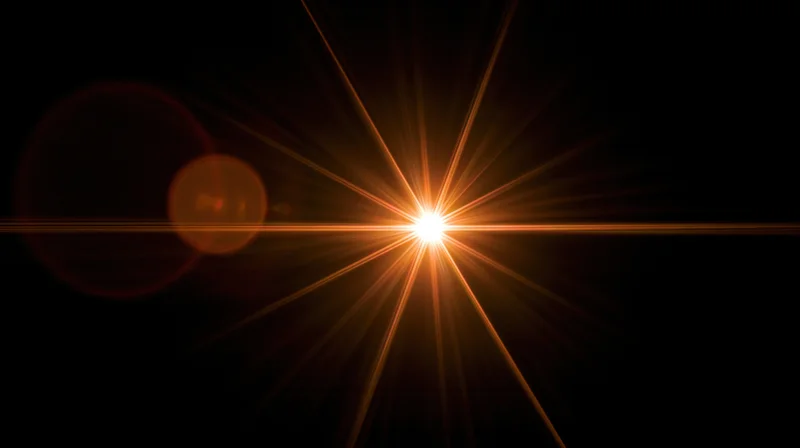 Bright starburst light flare radiating from center against dark background with copyspace