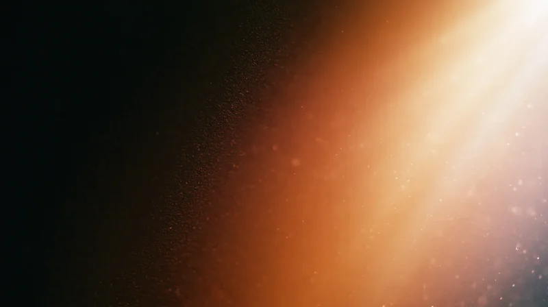 Warm glowing light radiating across a dark background with floating particles