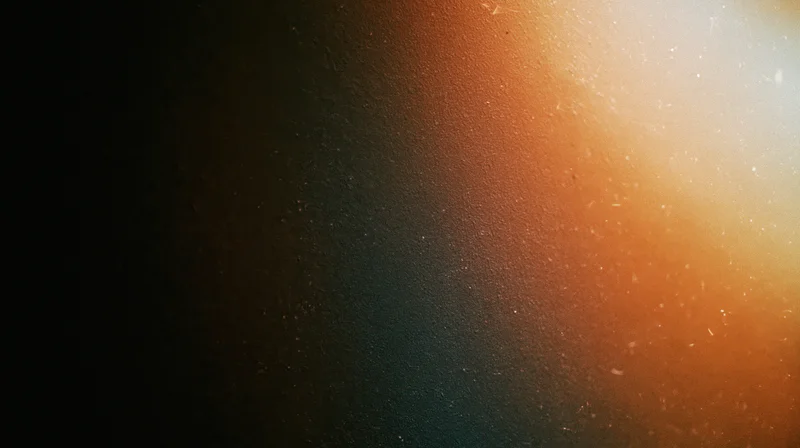 Warm orange light gradient with soft glow and floating particles on dark textured background