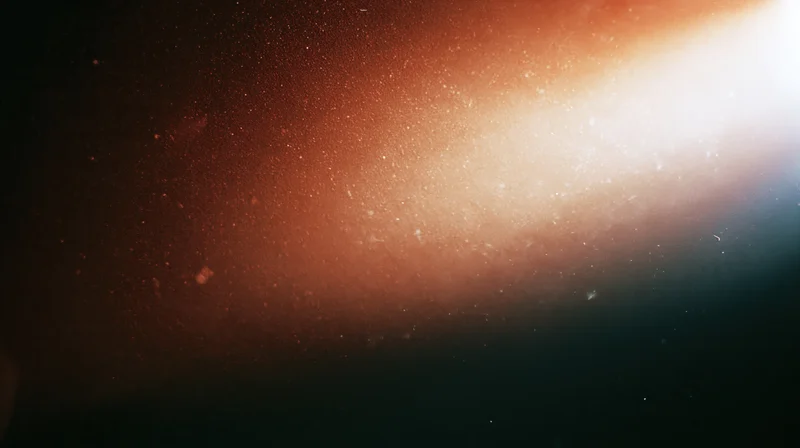 Glowing orange light with floating particles in dark space