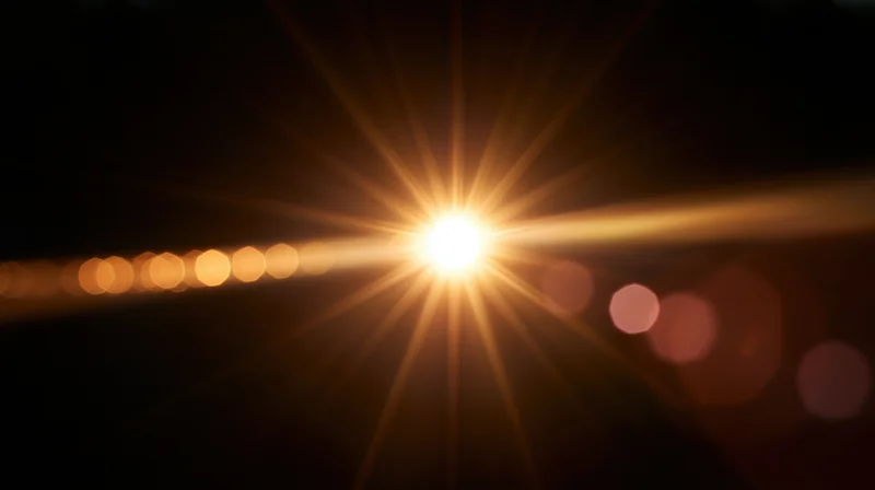 Bright light source with starburst flare and bokeh circles on dark background