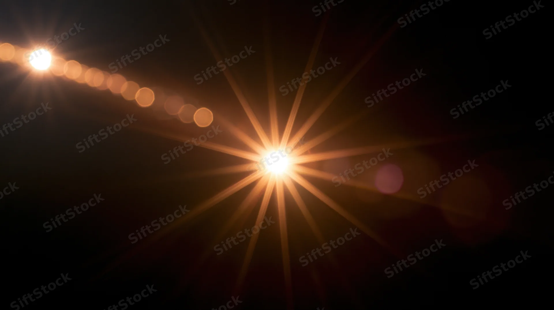 Bright light source creating starburst flare and bokeh circles against dark background