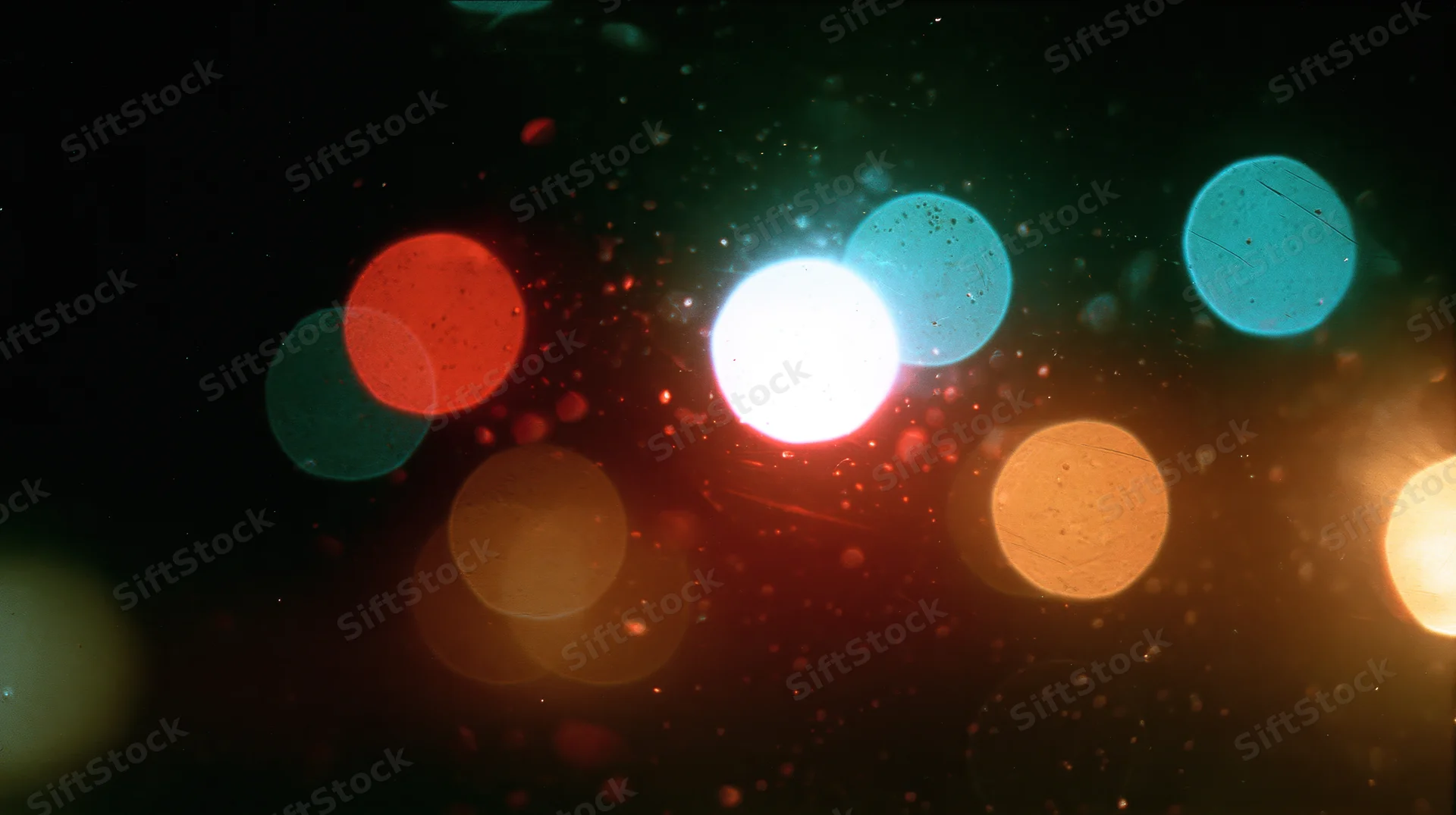 Blurred circular lights in warm and cool tones against a dark background with floating particles