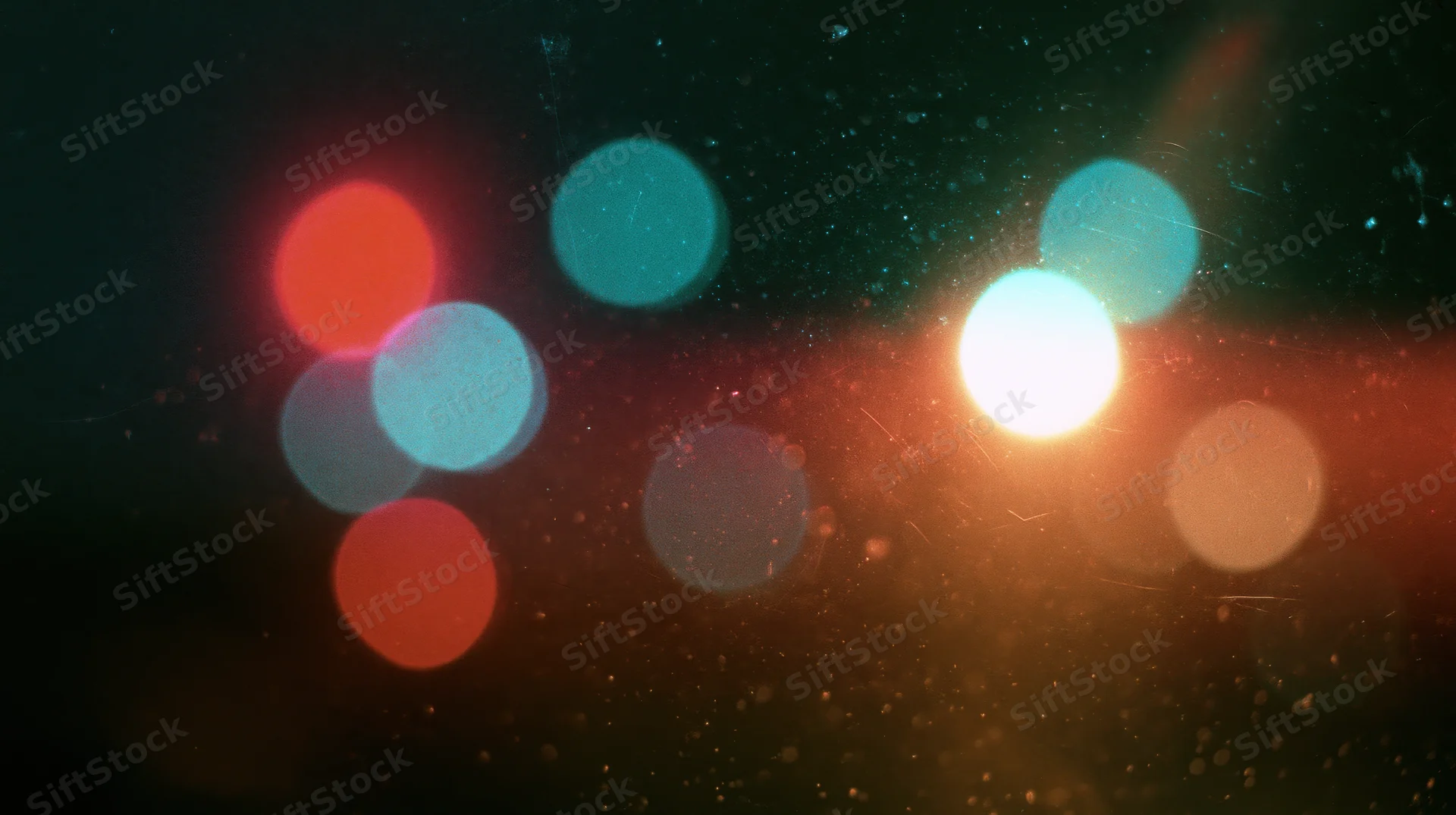Blurred circular lights in warm and cool tones against a dark background with visible dust particles and lens flare