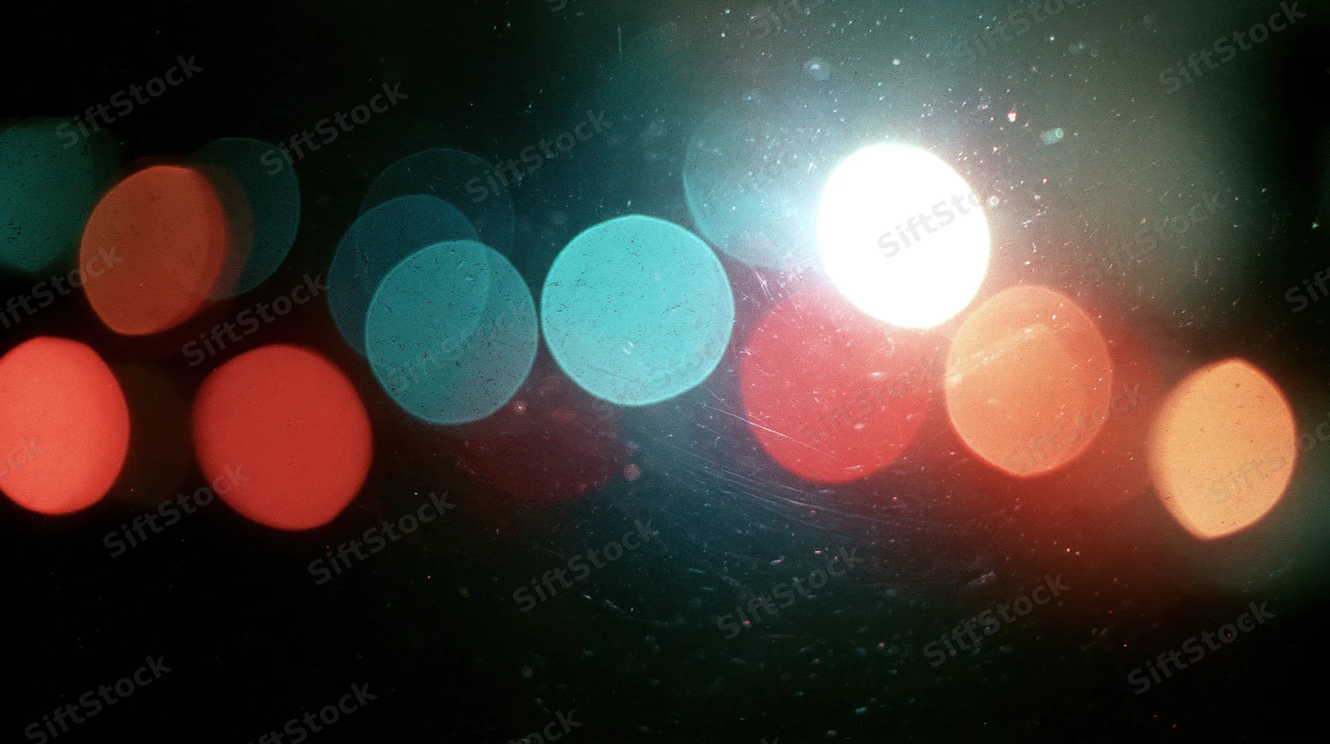 Blurred circular lights from traffic at night seen through a wet window