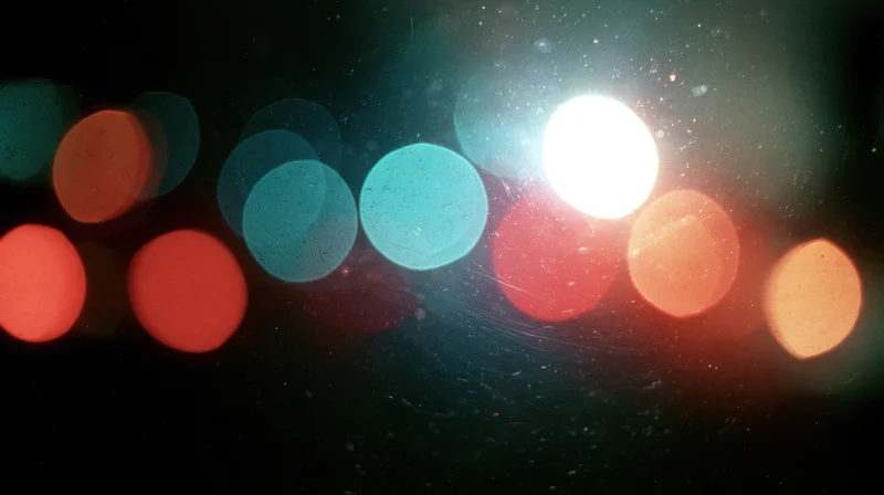 Blurred circular lights from traffic at night seen through a wet window