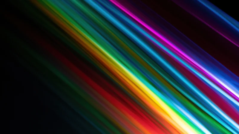 Diagonal streaks of rainbow light across a dark background with copyspace