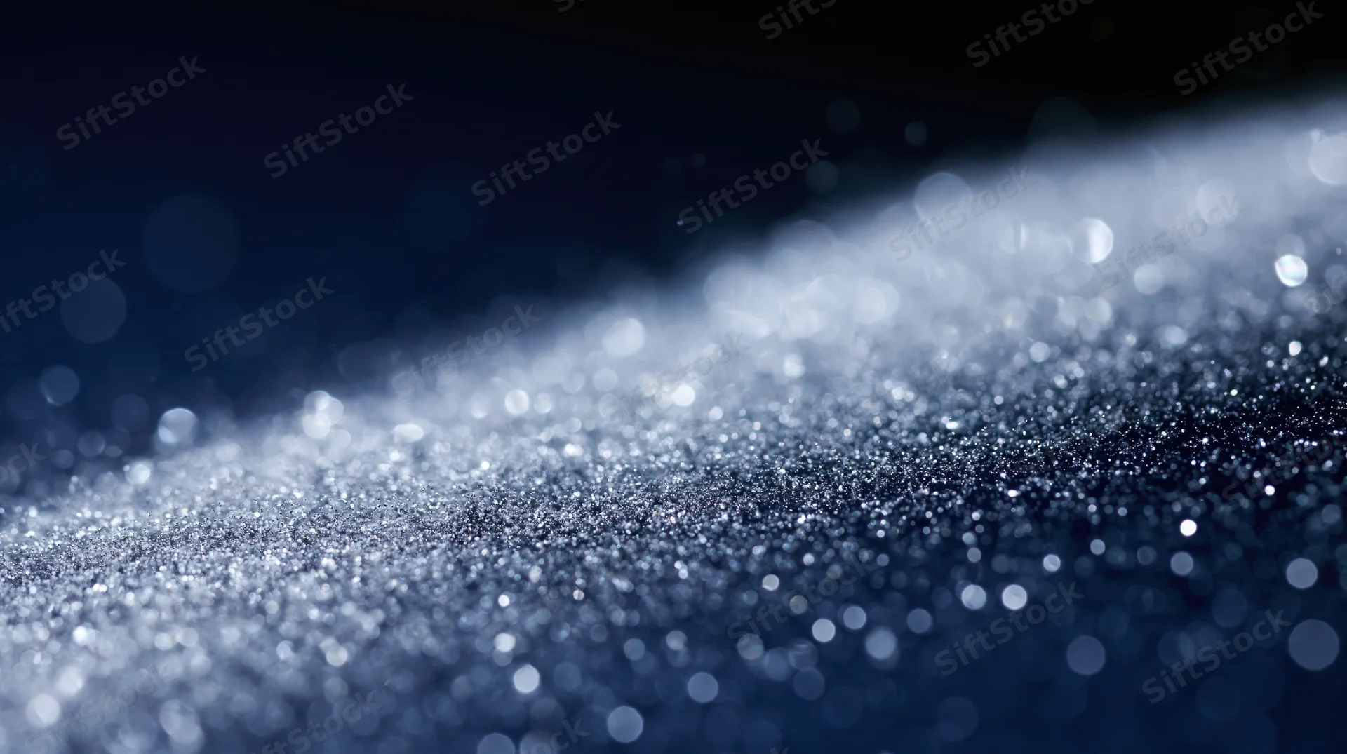 Glittering particles scattered across a dark surface with bokeh lights in the background