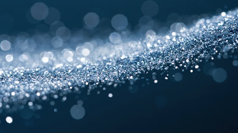 Shimmering silver glitter particles in motion against a dark blue bokeh background