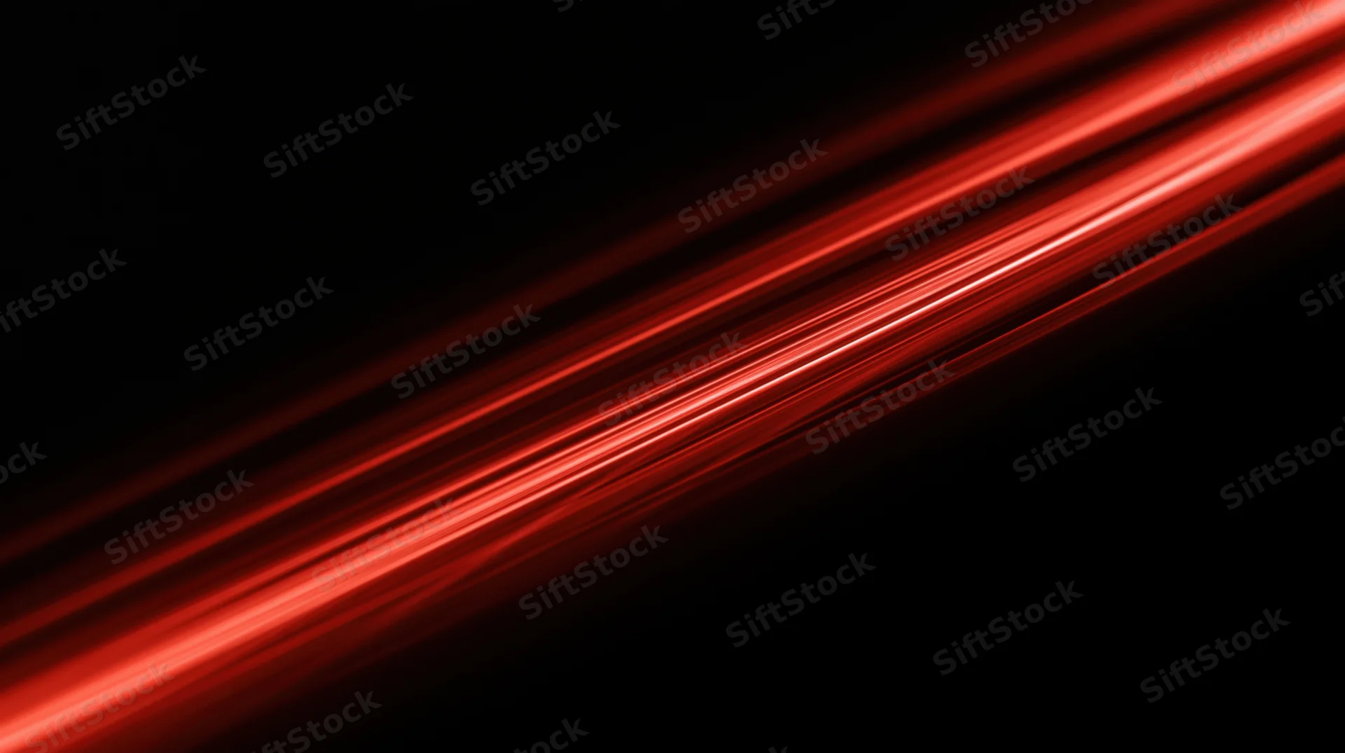 Diagonal red light streaks moving across a black background with motion blur