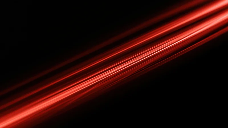 Diagonal red light streaks moving across a black background with motion blur