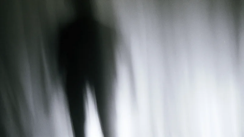 Blurred silhouette of a human figure in motion against a light gradient background