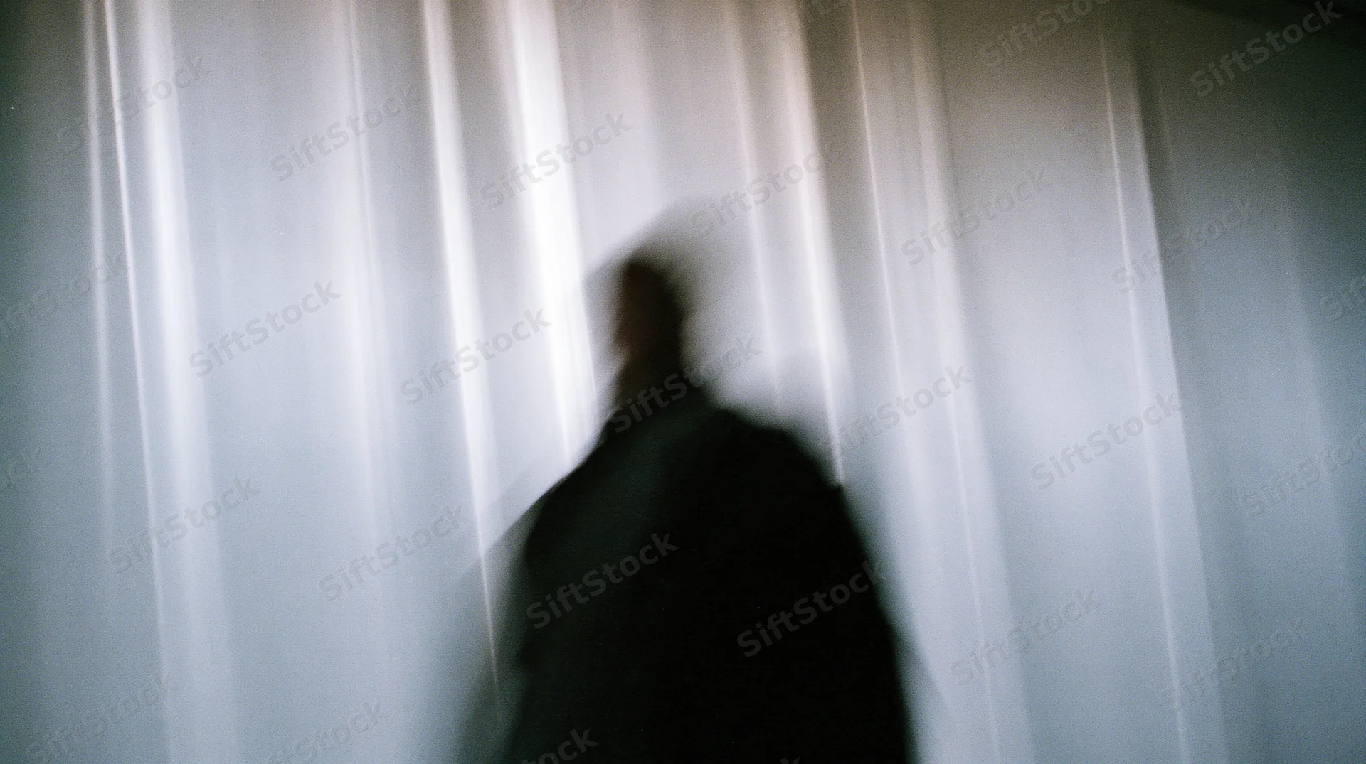 Blurred silhouette of a person in motion against a vertical light-streaked background