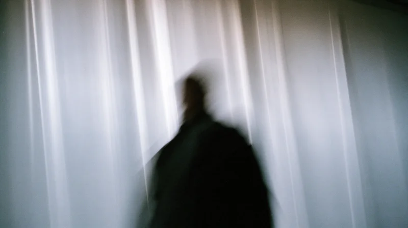 Blurred silhouette of a person in motion against a vertical light-streaked background