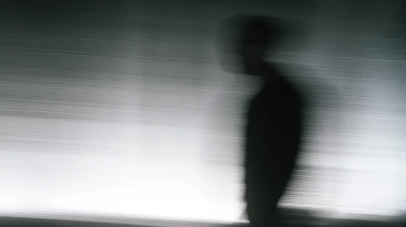 Blurred silhouette of a man in motion against a light gradient background