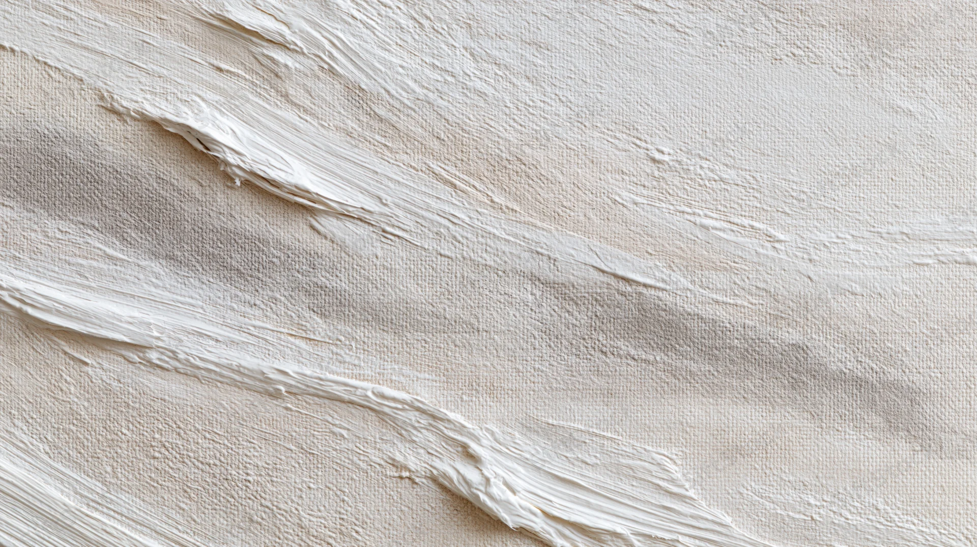 Close-up of white paint applied in textured brushstrokes on a wall surface