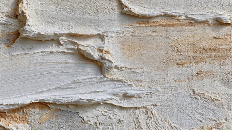 Closeup of cracked and peeling white plaster on a weathered wall surface