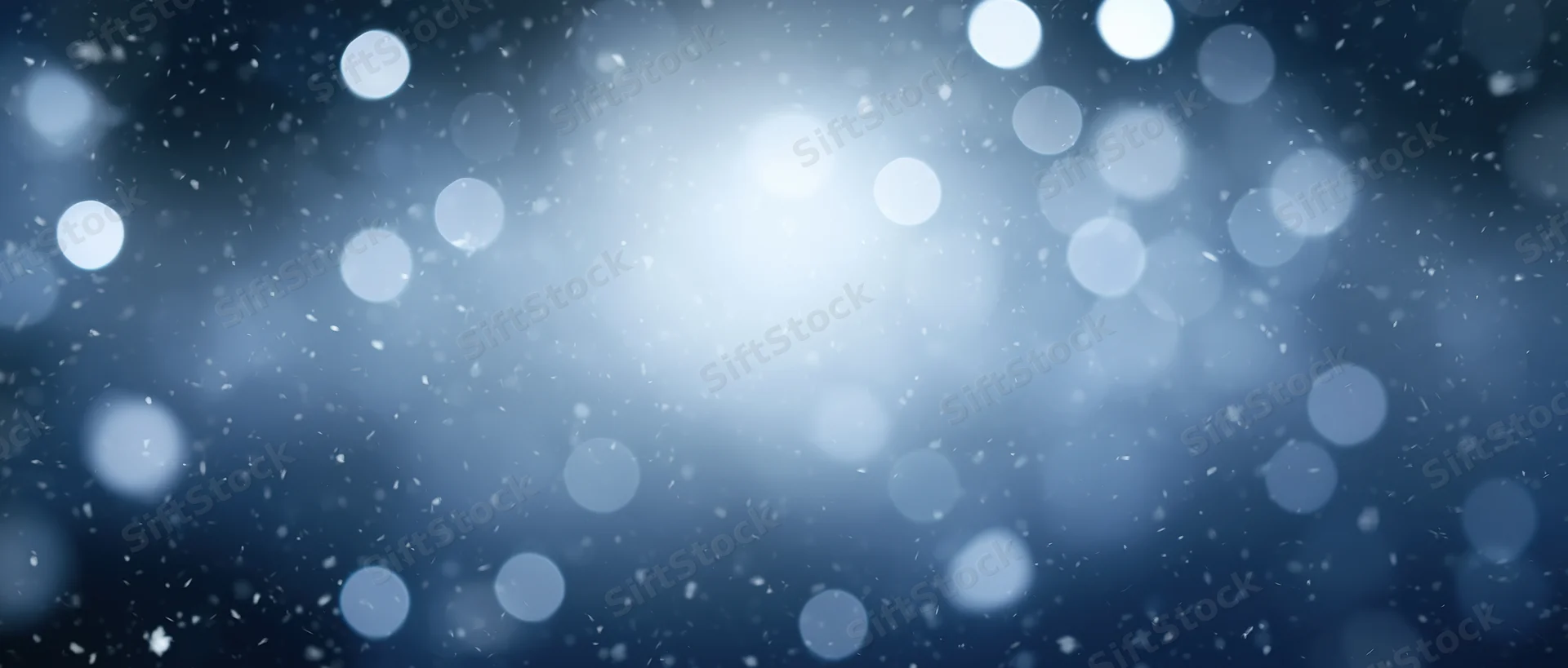 Blurred bokeh lights with falling snow in a dark blue winter background
