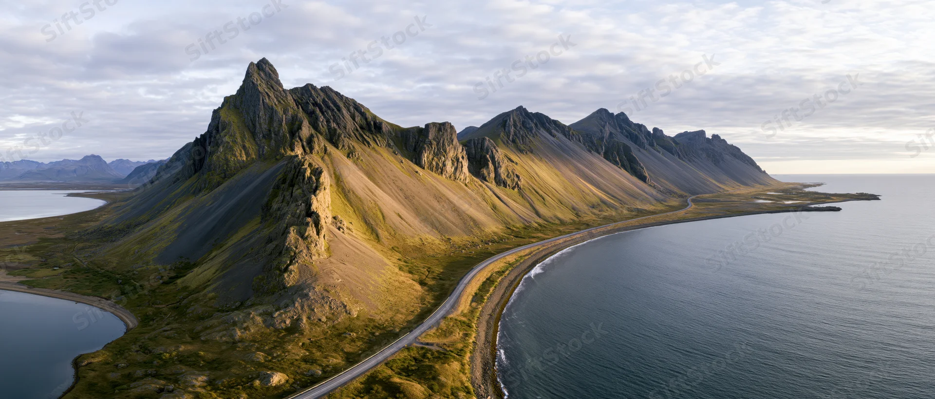 Rugged mountain range along a winding coastal road in Norway
