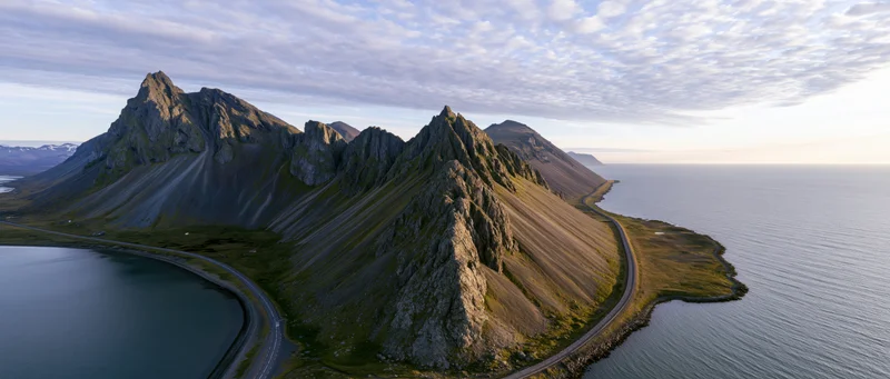 Rugged mountain peaks along a winding coastal road in Norway at sunset