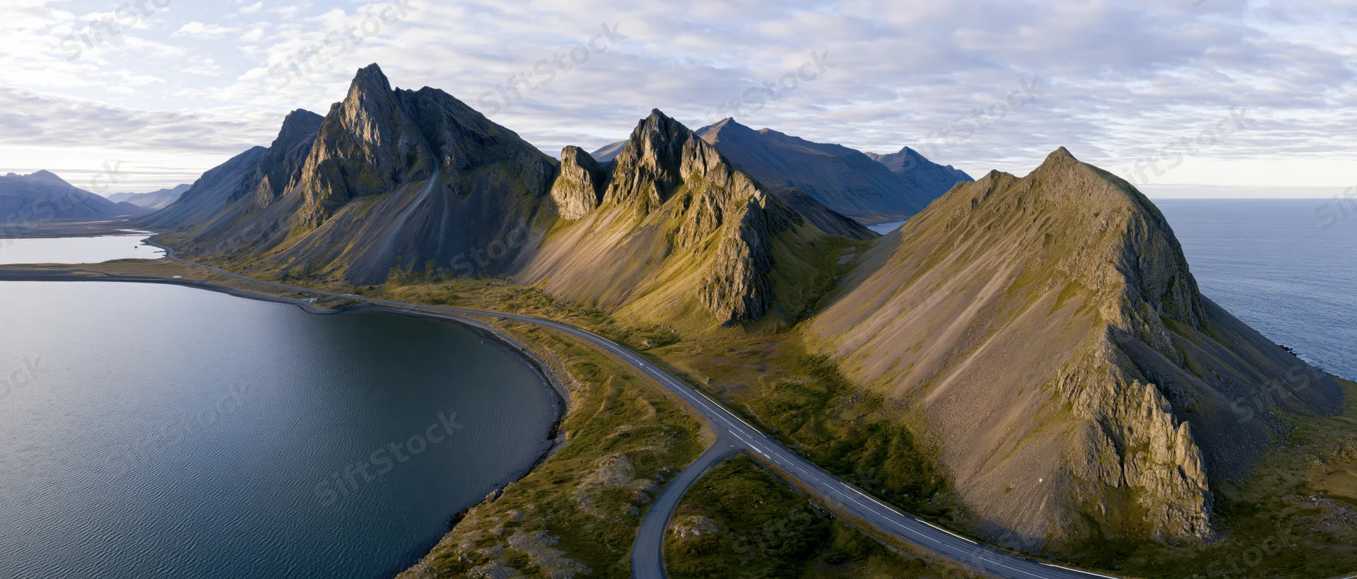 Winding road along a fjord between rugged mountains and the ocean in Norway