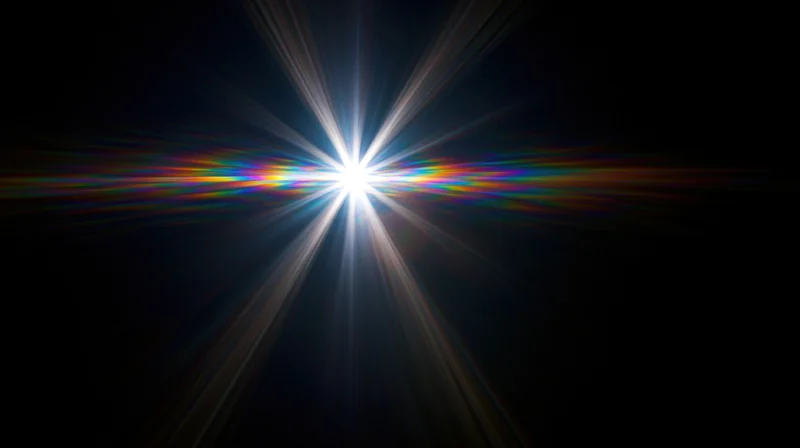 Bright starburst light flare radiating from center against dark background with rainbow spectrum streaks