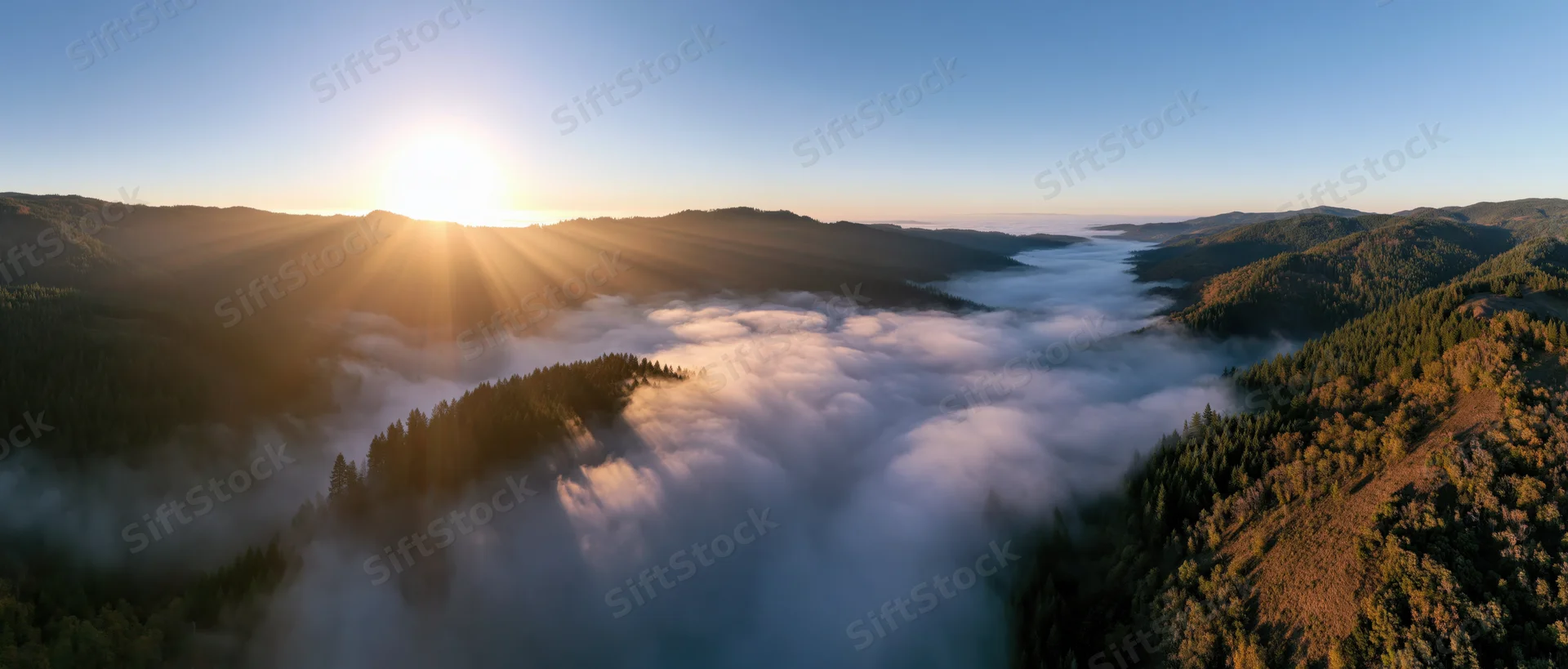 Sunrise over mountain valley with fog and forest from aerial view