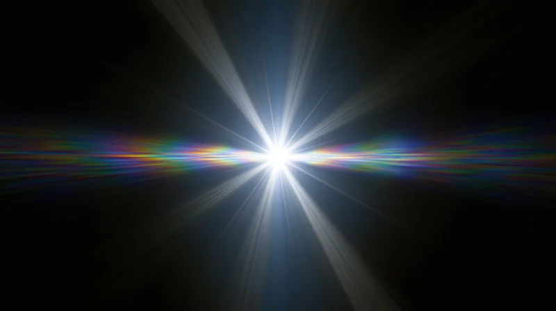 Bright white light burst with radial beams and rainbow flare against black background