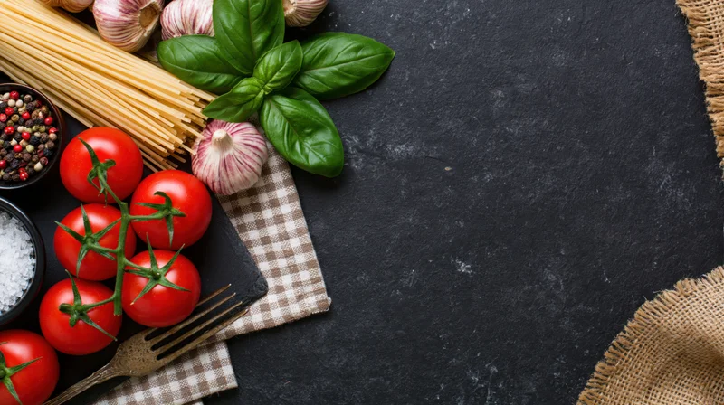 Fresh pasta ingredients arranged on a dark slate surface with copyspace