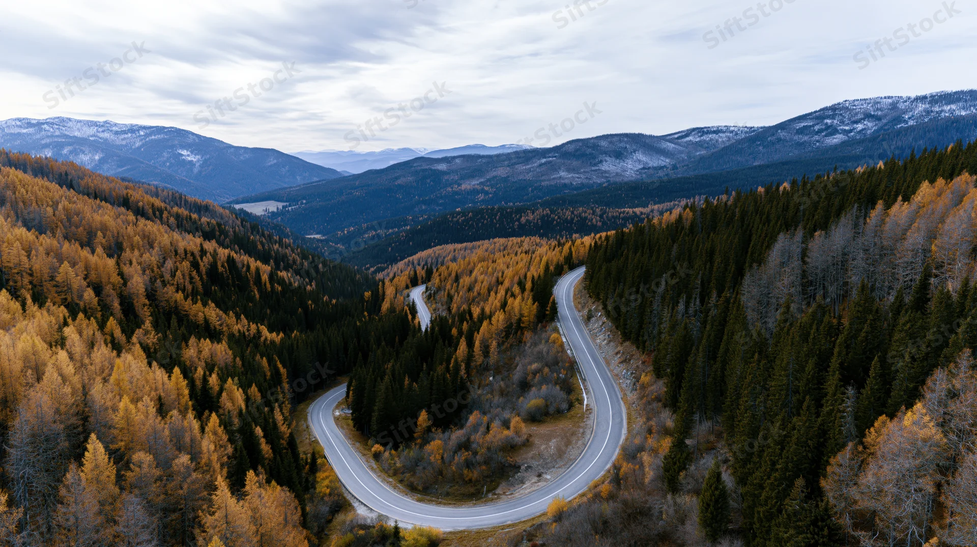 Winding road through autumn forest in mountain valley