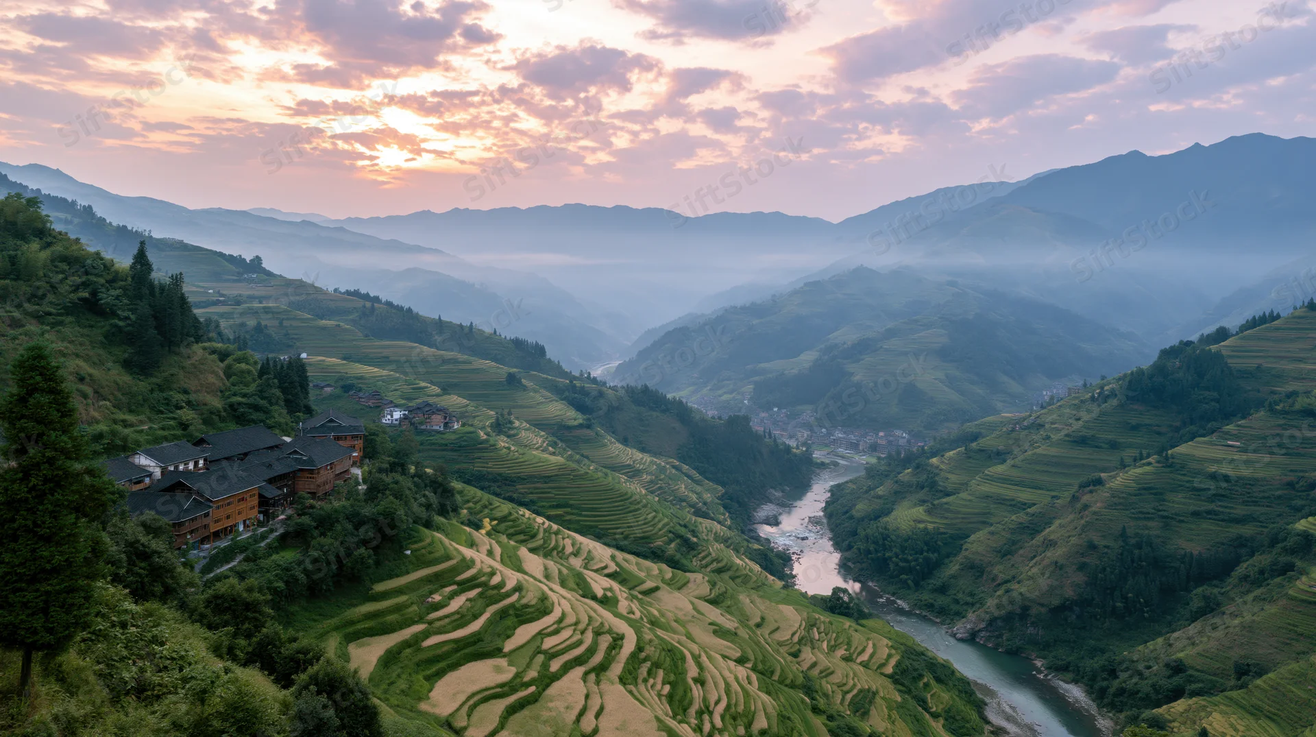 Terraced rice fields along a winding river in a mountain valley at sunset